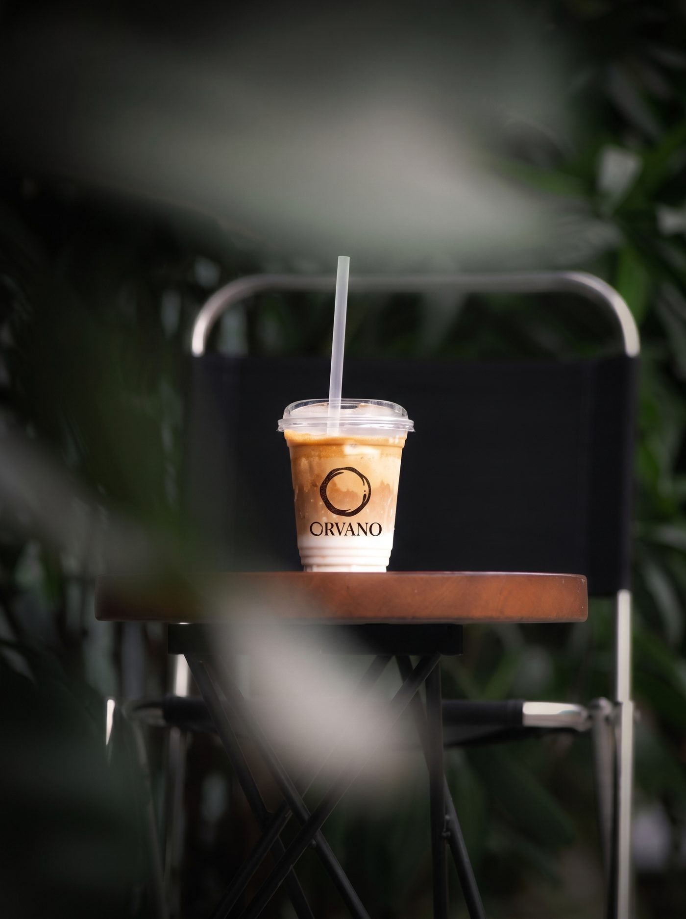 An ORVANO iced coffee on a café table beside greenery